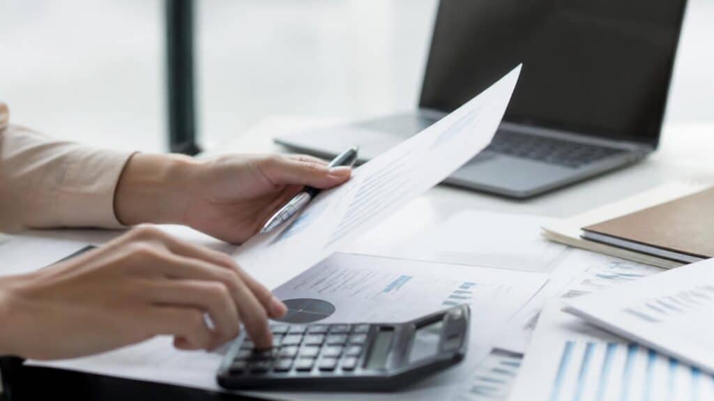 Close-up of hands reviewing rental income and cash flow calculations on paperwork at a desk